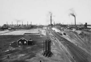 Blast Furnaces in the middle; refinery on the right; zinc plant on the left. Note ore trains on right and stack of refined lead on left.